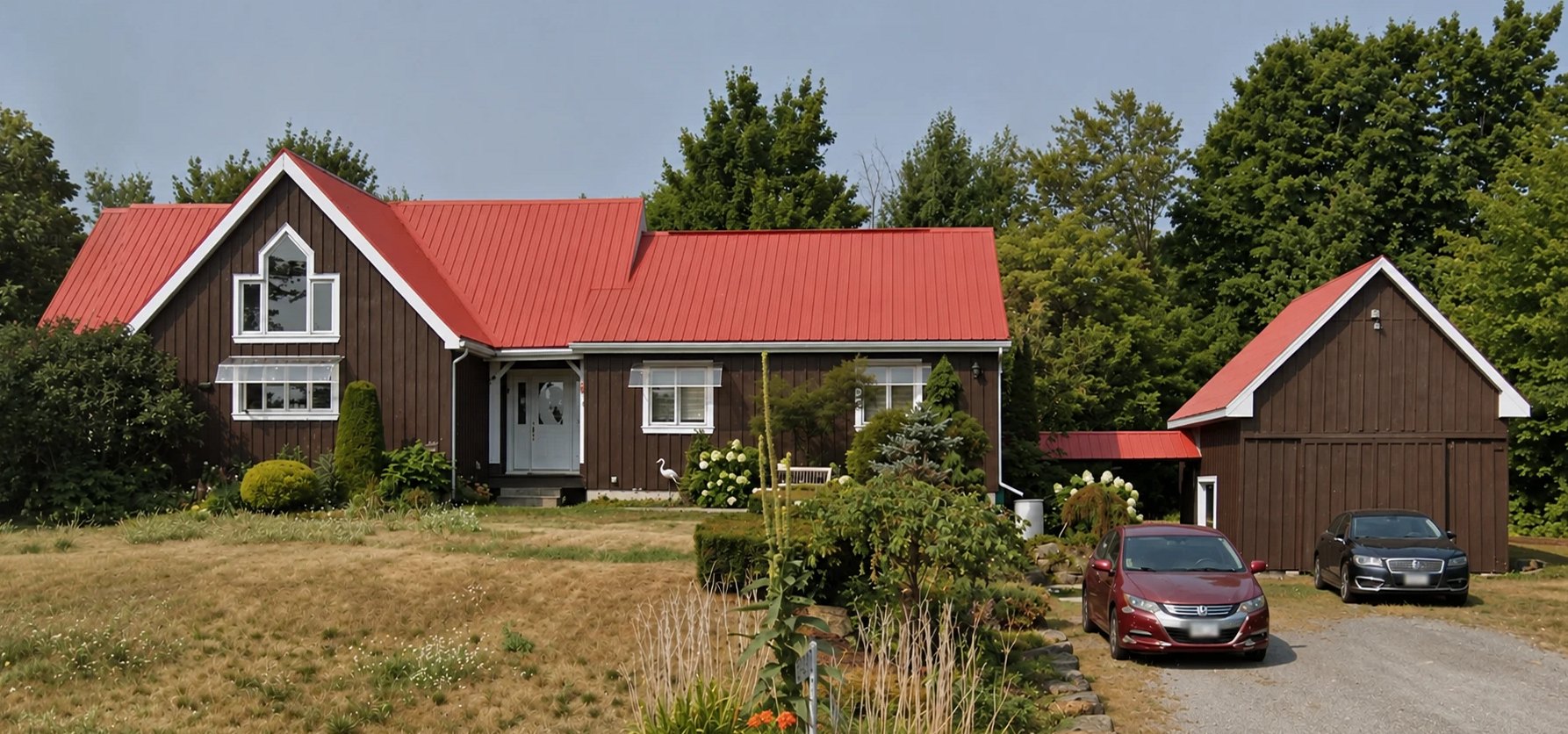 After: dark brown house with freshly painted white trim and red metal roof